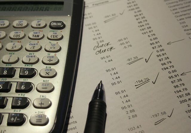 Foto mostrando um pedaço de uma calculadora científica, uma caneta e uma folha de papel com registros contábeis.