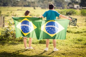 Casal de costas, cada um segurando uma bandeira do Brasil.