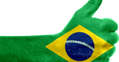 Mão com o polegar levantado em sinal de afirmação pintada com as cores e o desenho da bandeira do Brasil